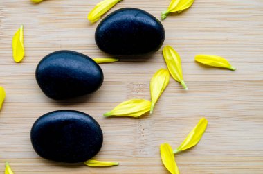 Tahtaya saçılmış sarı yapraklı üç zen taşının üst görüntüsü. Temiz görünüm ve metin için özelleştirilebilir alan..