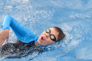 Close-up action portrait of a young swimmer while swimming freestyle in the swimming pool clipart