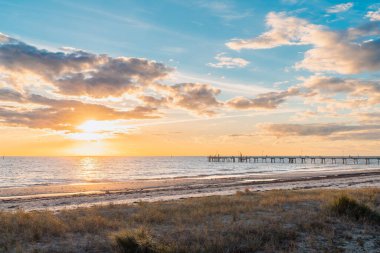 Glenelg Sahili, iskeleli ve arka planda insan siluetleri var. Günbatımında, Güney Avustralya.