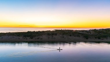 Güney Avustralya, Güney Liman 'da, alacakaranlıkta Onkaparinga Nehri boyunca yüzen bir adamın silueti.
