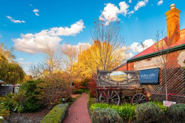 Hahndorf German Village, Adelaide Hills, South Australia - May 1, 2021: Old Hahndorf Village Market sign on vintage cart in autumn garden viewed from the Main street clipart