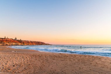 Southport plajı, Port Noarlunga, Güney Avustralya 'da sörf ve kürek sporu yapan insanlar.