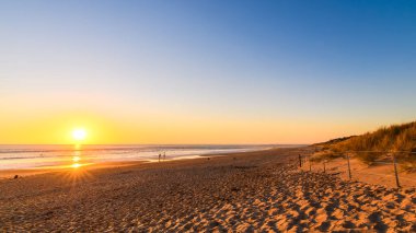 Port Noarlunga plajı, günbatımında insanlarla, Güney Avustralya