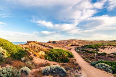 Güneş doğarken, Güney Avustralya 'nın Guichen Körfezi' nde, engebeli kireçtaşı sahili boyunca okyanus manzaralı Obelisk ile Robe Sahil Yürüyüşü