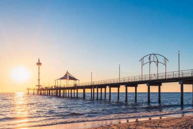 Günbatımında Brighton Jetty ile insanlar gün batımında plajdan izlerlerken, Güney Avustralya