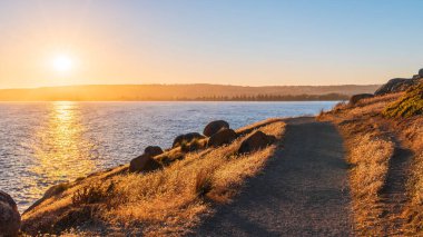 Günbatımında Granit Adası kıyısı boyunca manzaralı patika, Encounter Bay, Güney Avustralya