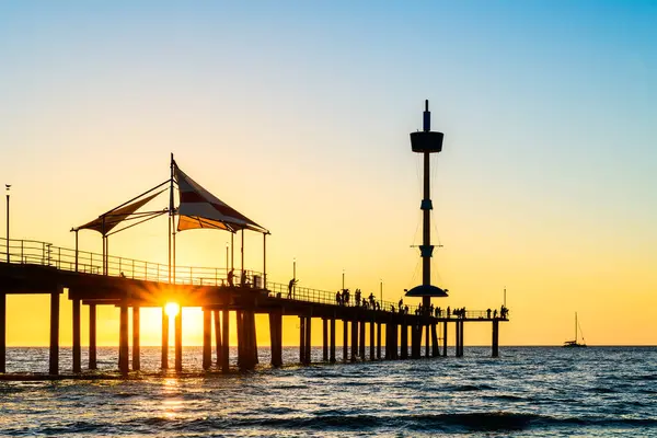 Brighton Jetty, sıcak bir yaz akşamında güneş ufukta belirdiğinde plajdan insanların siluetlerini izledi..