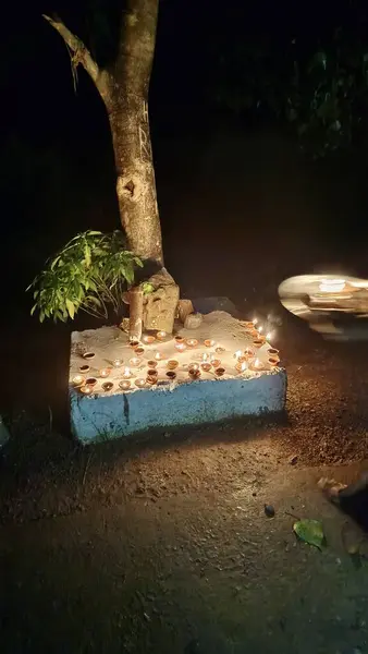 Ağacın etrafındaki mum ve eski küçük heykel.