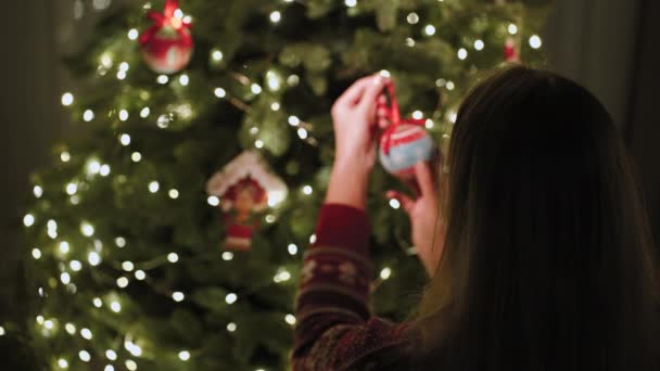居心地の良い家庭的な雰囲気の中で 女の子は美しいおもちゃでクリスマスツリーを飾ります — ストック動画