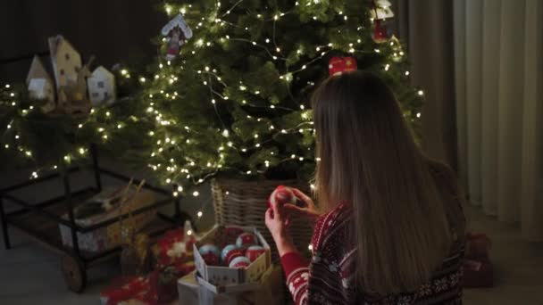 女の子は新年のおもちゃを見て クリスマスツリーに掛けます クリスマスの雰囲気 新年はちょうど角を曲がったところです スローモーション — ストック動画