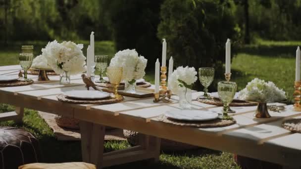 お祝いのイベントのコンセプト 絶妙な料理 ろうそく 明るい花で装飾されたオープンエアガーデンに美しくセットされたテーブルがあります カメラはゆっくりとテーブルから離れていく — ストック動画