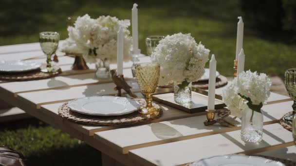 露天花园有一张布置精美的桌子 上面装饰着精美的菜肴 蜡烛和鲜艳的花朵 摄像机详细显示了桌子上的东西 相机玩具娃娃了 — 图库视频影像
