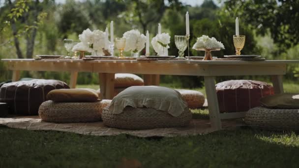 お祝いのイベントのコンセプト 絶妙な料理 ろうそく 明るい花で装飾されたオープンエアガーデンに美しくセットされたテーブルがあります カメラがゆっくりテーブルに近づく — ストック動画
