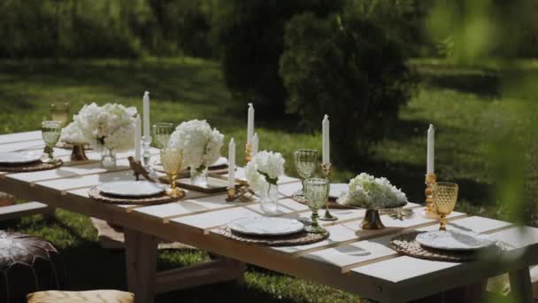 オープンエアガーデンには 絶妙なテーブルウェア ろうそく 明るい花で装飾された美しくセットされたテーブルがあります パーティー 結婚式のレセプション 銀河の宴会または他の休日のイベントのためのよい場所 — ストック動画