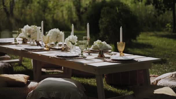 オープンエアガーデンには 絶妙なテーブルウェア ろうそく 明るい花で装飾された美しくセットされたテーブルがあります パーティー 結婚式のレセプション または他の休日のイベントのための良い場所 — ストック動画