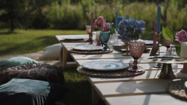 Kamera, açık hava bahçesindeki güzel dekore edilmiş bir ziyafet masası boyunca yavaşça hareket ediyor. Eski sofra takımı ve renkli çiçekler özel bir tatil ortamı yaratır.