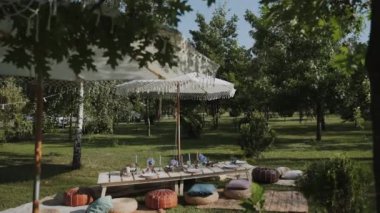 Açık hava bahçesinde güzel bir dinlenme odası var. Güneşin bir şemsiyesi, güzel bir setin üzerine bir gölge bırakır. Klasik tabaklar, zarif bardaklar ve güzel çiçekler..