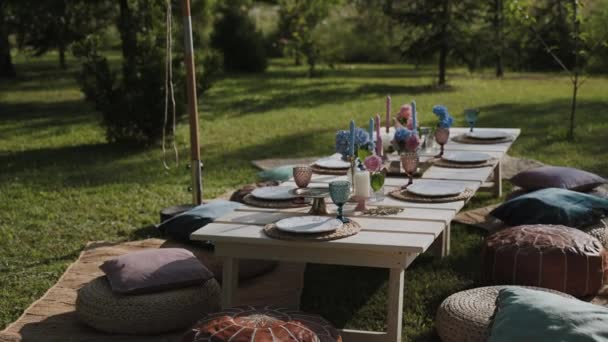 一个令人难以置信的风景 花园中央的一张节日餐桌 这个地方是你度假时用的 一张摆好的桌子 有老式的碗碟 各种坐用的地毯和袋椅 — 图库视频影像