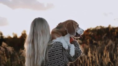 Bir kadın yorgun köpeğini kollarına aldı, tarlada yürüyorlar. Dili dışarı fırlamış bir köpek çok komik görünüyor. Konu için iyi bir konsept.