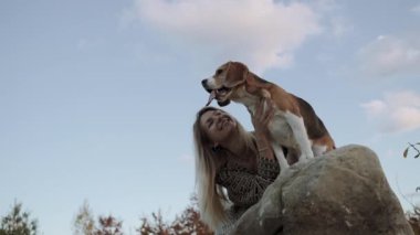 Güzel bir kadın evcil hayvanının arkadaşlığından hoşlanır. Bir kadın bir köpeği okşuyor ve gülümseyerek ona bakıyor. 