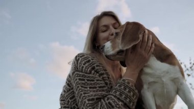 Güzel bir kadın evcil safkan Beagle 'ına sarılıyor. Kız köpeği okşar. Kavram, köpek insanların en iyi dostudur. Yakın plan.