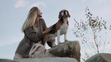 Kavram, köpek insanın en iyi dostudur. Güzel genç bir kadın evcil hayvanını okşuyor, safkan bir av köpeği, büyük taşların üzerinde oturuyorlar. Hayvanınla bir akşam yürüyüşü. Yakın plan.