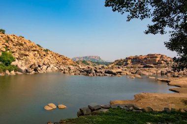 Tungabhadra nehri Hampi 'nin kayalıklarından akıyor. Vijayanagara İmparatorluğu 'nun başkenti Hampi, UNESCO' nun Dünya Mirası sitesidir..