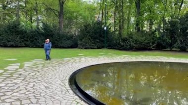 Berlin 'deki Tiergarten' de bulunan Simsonweg 'deki Ulusal Sosyalizm' in Sintii ve Roman Kurbanları Anıtı. Ortasında üçgen bir taş bulunan koyu, dairesel bir havuzdan oluşur..