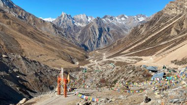 Om Parvat 'a giden yolda bayraklı ve tapınak çanlı kutsal kapı. Arka planda yılan şeklinde bir dağ olan Sheshnag Parvat