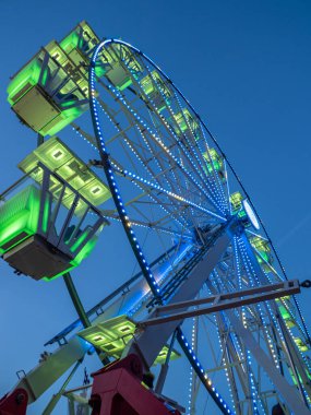 Mavi gökyüzünde yeşil ışıklı dönme dolap.