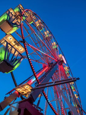 Mavi gökyüzünde pembe ışıklı dönme dolap.