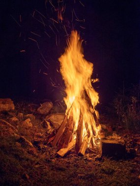 Odunlar karanlıkta kamp ateşinde yanıyor.