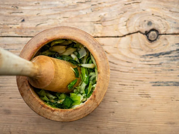 crushed garlic in a wooden mortar and pestle on wooden table