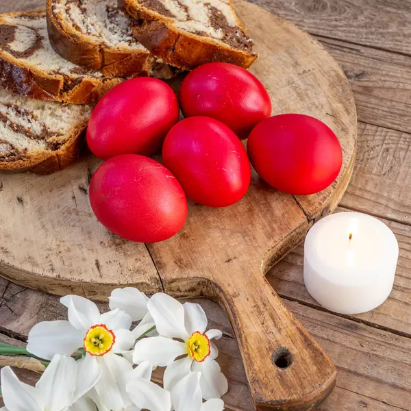 Geleneksel Romen Paskalya yemeği ya da ahşap masa ve renkli paskalya yumurtaları ve beyaz narsist çiçekleri üzerinde tatlı ekmek