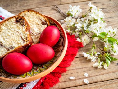 Çiçek açan dalların yanında kırmızı Paskalya yumurtaları ve üzerinde tatlı sünger pastası olan tabaklar ya da ahşap masa üzerinde hindistan cevizi.