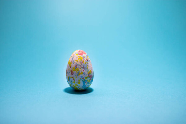 Пасхальное разноцветное яйцо на бирюзовом голубом фоне