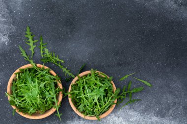 Siyah arka planda, tahta tabaklarda taze roka. Sağlıklı yemek, en iyi manzara..