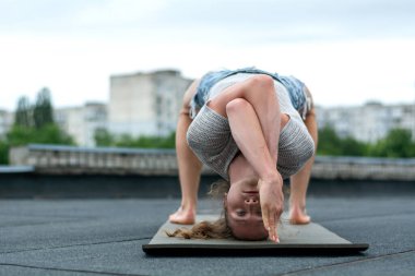 A man practices yoga on the roof of the house. Yoga at sunset. Healthy life, sport and meditation concept