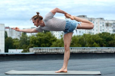 Adamın biri evin çatısında yoga yapıyor. Gün batımında yoga. Sağlıklı yaşam, spor ve meditasyon konsepti