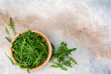 Taze roka yaprakları ahşap kasede beton arka planda. Üst görünüm.