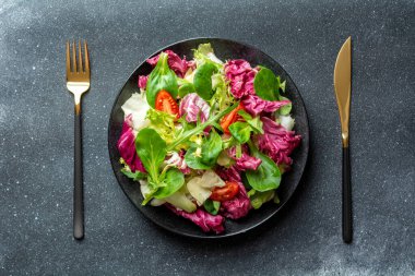 Lahanalı salata, turşu ve siyah tabakta domates.