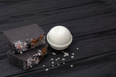 Siyah ahşap arka planda el yapımı sabun ve tuz. Boşluğu kopyala.