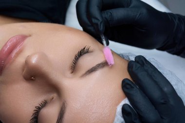 Bir güzellik uzmanı müşterisinin kaşlarını fırçalar. Kuaförde kaş bakımı prosedürü.