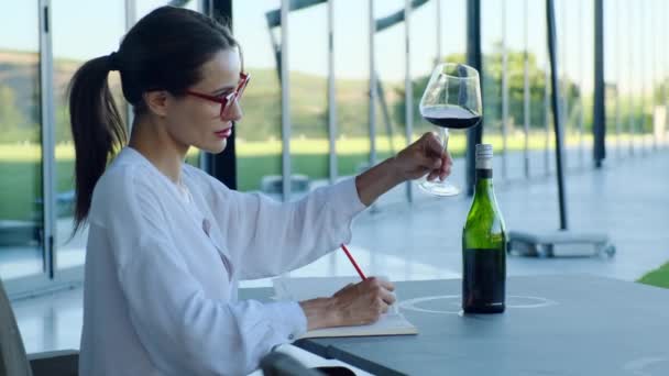 专栏作家女性持酒杯红酒品酒品评卡 年轻女子在酒窖里喝红葡萄酒特别香 — 图库视频影像