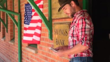 Vahşi batıdaki Teksaslı bankacı para kasasından kredi veriyor. Nüfuslu batı kasabasında ekose gömlekli bir kovboy meyhanede oturur ve para sayar. Vahşi batı kasabasının caddesinde banka binası var.