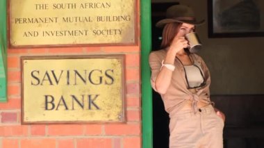 Kovboy kız Güney Afrika 'da bir bankanın yanında duruyor. Şapkalı ve rom içiyor. 