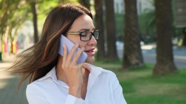 快乐的年轻亚洲女人一边打电话一边笑 在市中心 穿着白衬衫的时髦而成功的拉丁女人在电话里交谈 他的年轻女商人用智能手机 — 图库视频影像