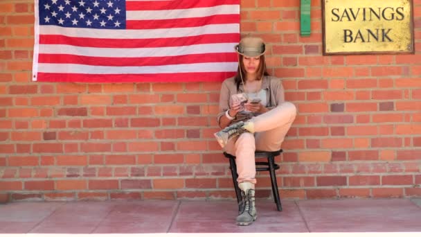 西部城镇 木结构古老 一个戴帽子的女人坐在德克萨斯一家银行旁边数钱 狂野的西部沙漠和城市街道 有天主教教堂 警长办公室 银行和酒店 — 图库视频影像