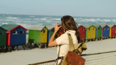 Sırt çantalı kız turist renkli evlerin yanındaki sahilde duruyor. Sinema ve ilham verici seyahat blogcusu canlı motivasyon macerası. Yeni nesil yeni konsept seyahatler. Heyecanlı dünya kaşifi