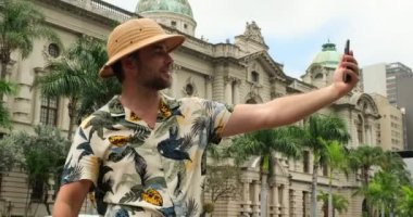 Seyahat kıyafeti giymiş bir gezgin Madrid 'in ortasında telefonuyla fotoğraf çekiyor. Amerikalı erkek gezgin parkta oturur ve dinlenir ve tatil sırasında mimarinin tadını çıkarır. Avrupa 'da erkek gezgin